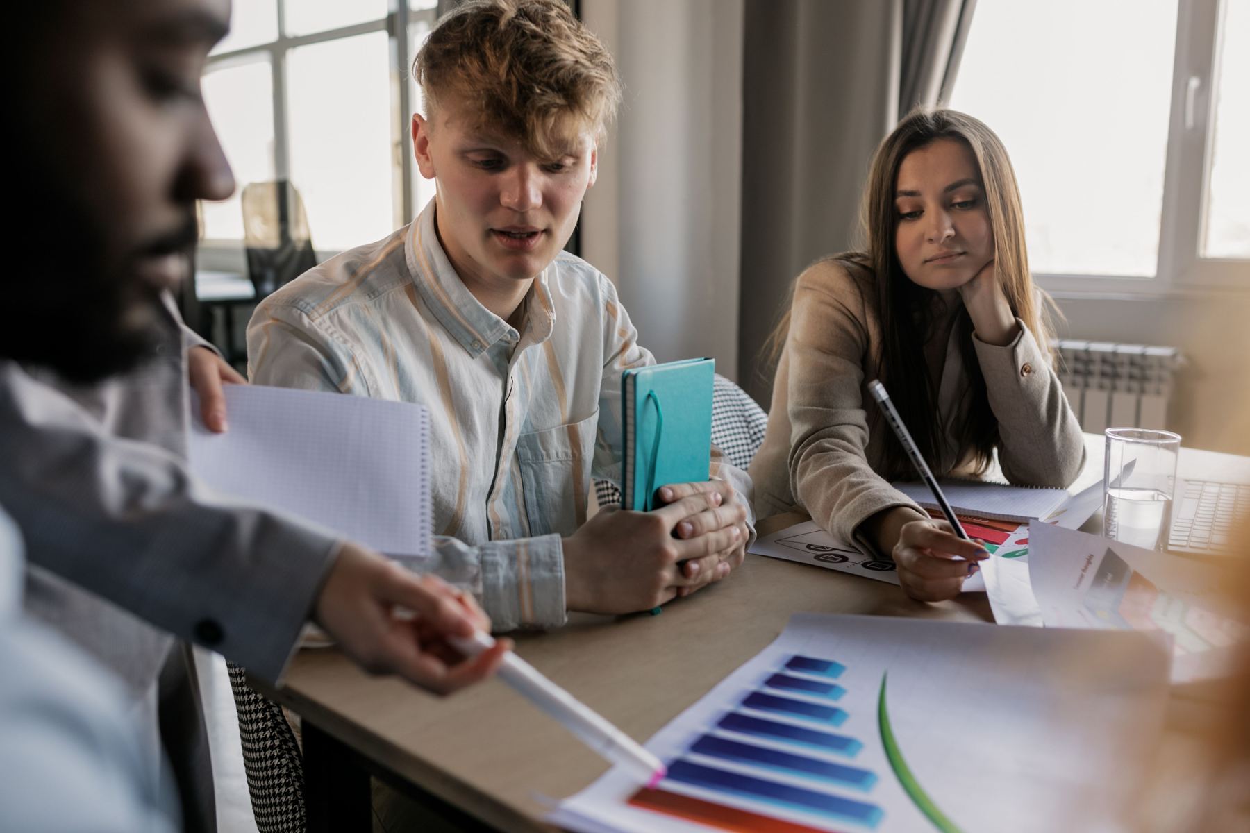 Three colleagues reviewing a printed bar chart together at a wooden table